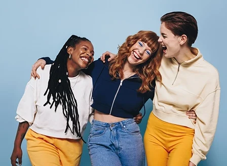 Multicultural female friends laughing and having fun while embracing each other.