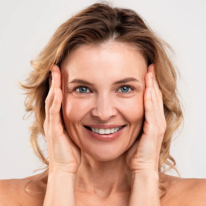 Beautiful Middle Aged Woman Touching Her Face And Smiling At Camera