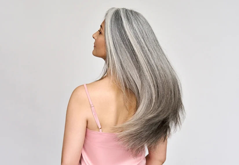 Back view of senior mature middle aged older Asian lady with long gray natural coloring vibrant silky hair.