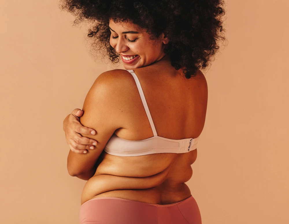 Self-loving plus size woman smiling happily while wearing underwear.