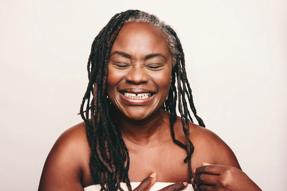 Cheerful mature woman laughing happily while wrapped in a bath towel
